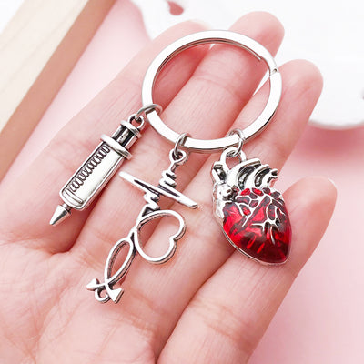 Image 1 showing a hand holding two different types of scissors and heart shaped keychais.