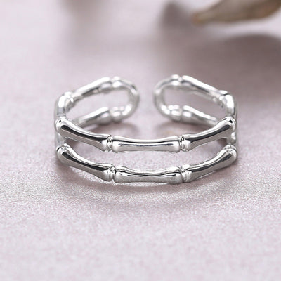 White gold dual bamboo open adjustable ring on soft pink surface