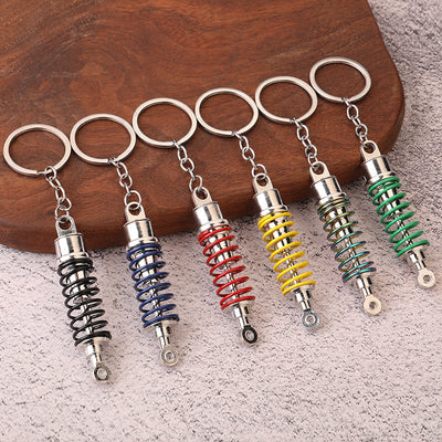 Six shock absorber keychains with black, blue, red, yellow, iridescent, and green coils.