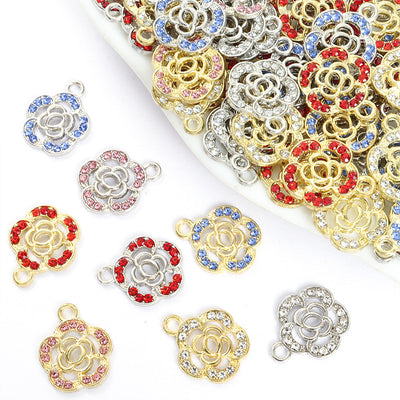 Assorted crystal camellia flower charms arranged beside a tray on white