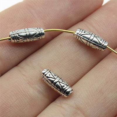 Hand-held front and back view of engraved geometric tube small-hole bead in two antique finishes