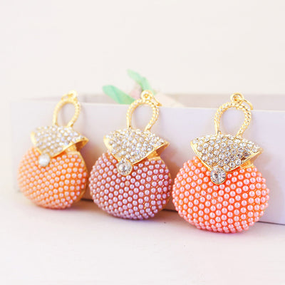 Three pearl-like bead handbag charms in peach, purple, and pink with clear rhinestone flaps.