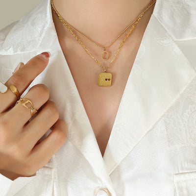 Gold layered YOU ME square and O pendant worn white satin shirt