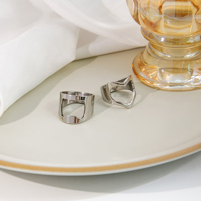 Two angles of silver hollow heart geometric rings on cream plate