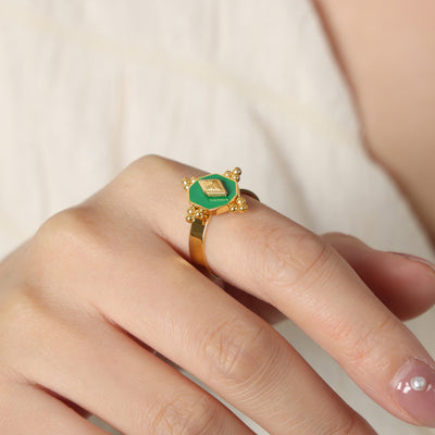 Hand wearing gold green enamel hexagon open ring close-up