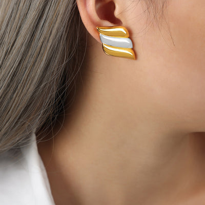 Two-tone gold and silver three-layer wing stud earring worn on ear