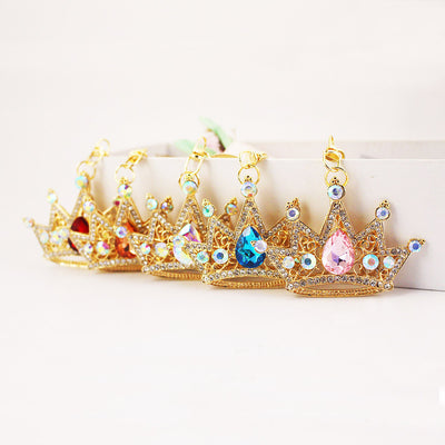 Several gold-tone crown charms with different colored teardrop gems arranged in a row.