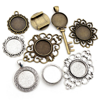 Assorted ornate round and key-shaped pendant bezel trays arranged together on a plain background