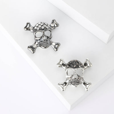 Black and silver skull crossbones brooches pair on white blocks