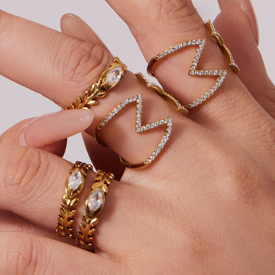 Styled hand view of crystal cross and leaf band open rings in main image 1.