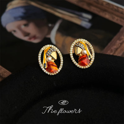 Gold-tone red-dress-woman portrait-pearl studs in the first product display.