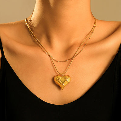 Gold quilted heart pendant layered with satellite chain on model