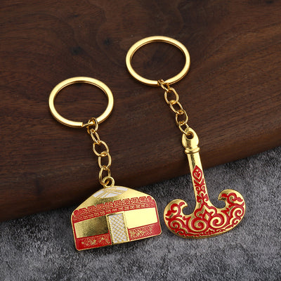 Two gold-tone key rings with a red and white yurt charm and a curved red ornamental pot charm.