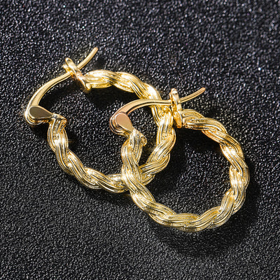 Gold twisted rope hoop earrings pair on dark glitter surface