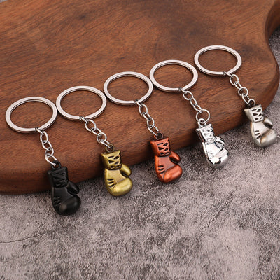 Five boxing glove keychains in black, gold, copper, bright silver, and antique silver finishes.