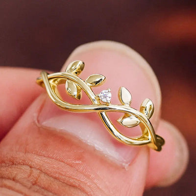 Gold vine leaf infinity ring with clear stone worn on fingertip