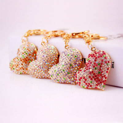 Four rhinestone heart keychains in pink, purple, peach, and iridescent colors arranged together.