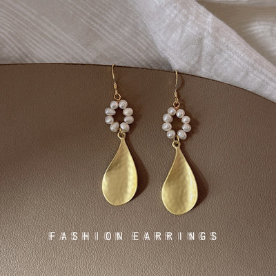 Pearl circle hammered gold teardrop earrings on taupe leather