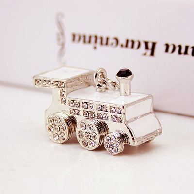 Close view of a silver-tone train charm with clear stones and white inset panels.