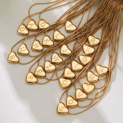 Assorted gold letter heart pendants arranged on white fabric