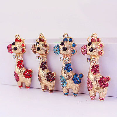 Four gold-tone giraffe charms display red, brown, blue, and pink rhinestone patterns.