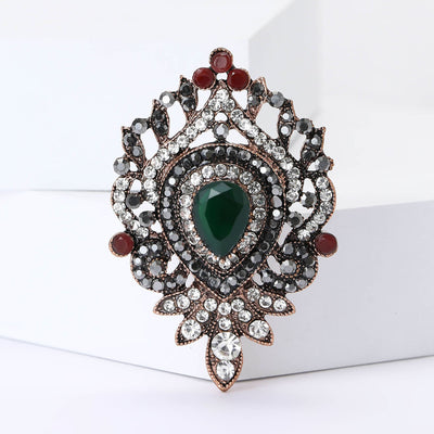 Front view of ornate oval medallion with a deep green center and red bead accents