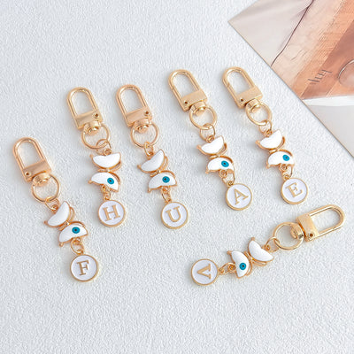 Several butterfly evil eye letter keychains in white enamel and gold tone