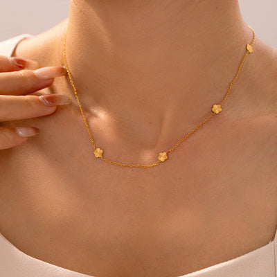 Model wearing gold flower station necklace on collarbone close-up