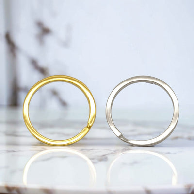 Gold-tone and silver-tone round split rings stand upright on a pale surface.