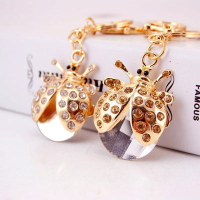 Two gold-tone ladybug charms with clear and amber rhinestones and faceted pendants.