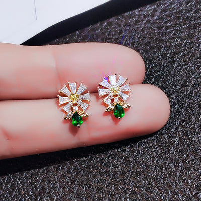 Gold daisy clear CZ green teardrop stud earrings held on fingertips