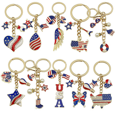 Front display of eight American flag wing and USA enamel keychains with visible colors and attached hardware