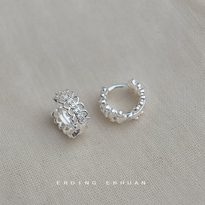 Silver lace-edge CZ huggie pair on beige linen