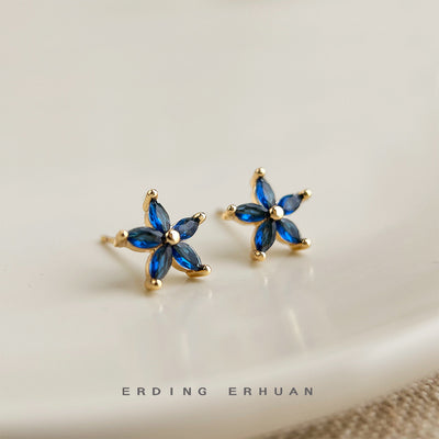 Blue five-petal gold flower studs on white ceramic plate