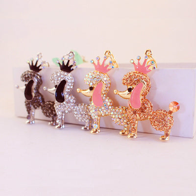 Four crowned poodle charms in peach, iridescent, clear, and dark rhinestone finishes.