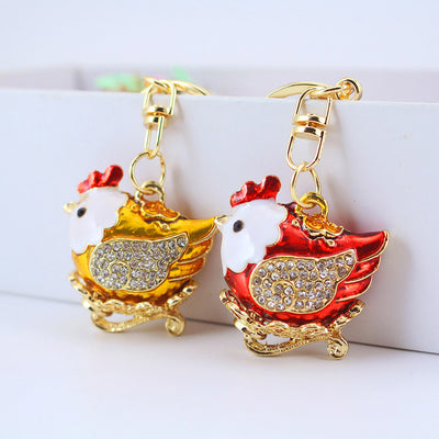 Red and gold-tone hen keychains displayed side by side from the front.