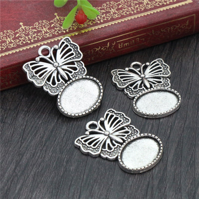Butterfly-shaped pendant with an oval cabochon tray below in a group view on a white background
