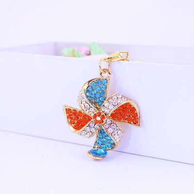Front view of a gold-tone pinwheel charm covered in red, blue and clear rhinestones.