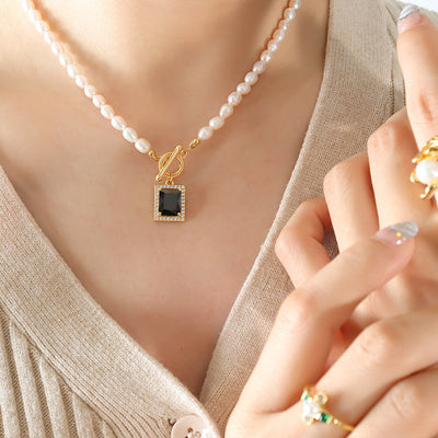Freshwater pearl necklace with black square pendant worn on beige knit