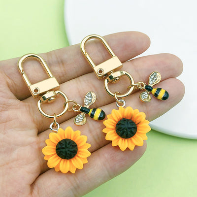 Image 1 showing a hand holding three sunflower charms.