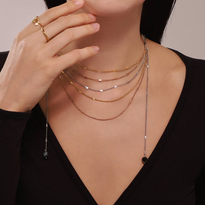 Layered multi-tone chains with dark stone tassel worn on neck