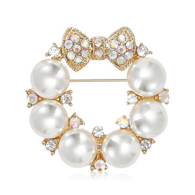 Gold pearl circle brooch with rhinestone AB bow on white background