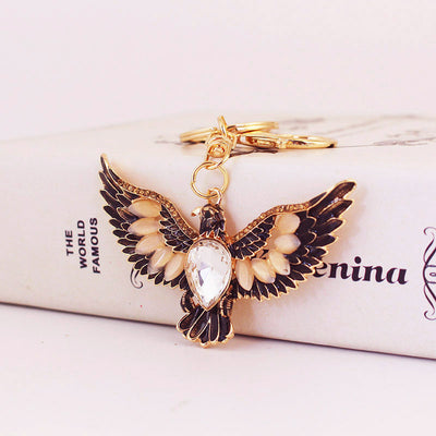 A clear teardrop-centered eagle keychain rests against a pale box.