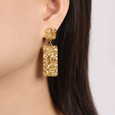 Model wearing gold molten texture rectangle drop stud earring