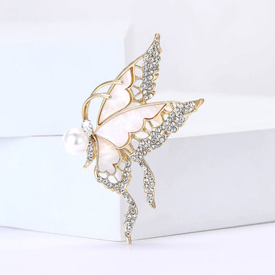 Front view of an airy gold-tone butterfly with clear crystals and a pearl accent