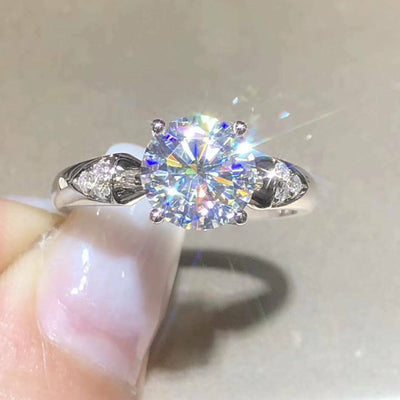 Silver round clear solitaire ring front view held by fingers with sparkle