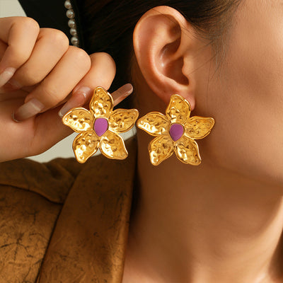Gold purple-center hammered flower studs worn on both ears