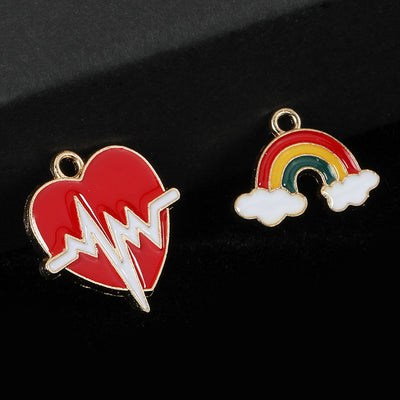 Red heartbeat heart charm beside a rainbow and cloud charm, both gold-tone framed