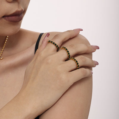 Model wearing two gold green glass eternity rings stacked on fingers
