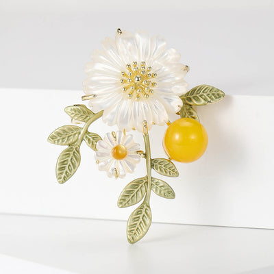 white daisy and yellow berry brooch with green leaves isolated on a white background